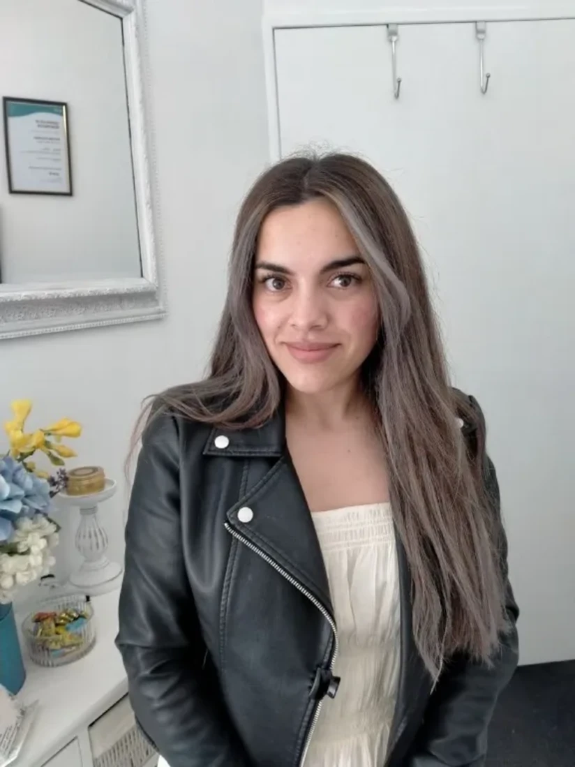 A client in a leather jacket over a cream top, her brows shaped and her lash extensions freshly applied